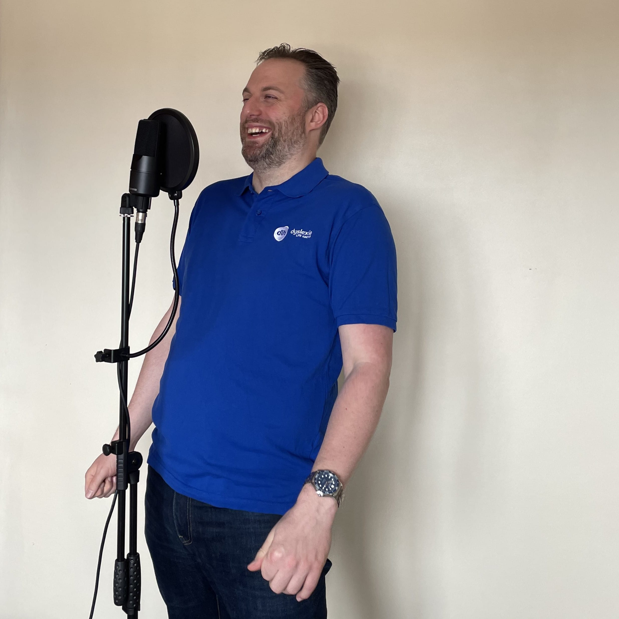 Matt Head in blue polo laughing behind the podcast microphone