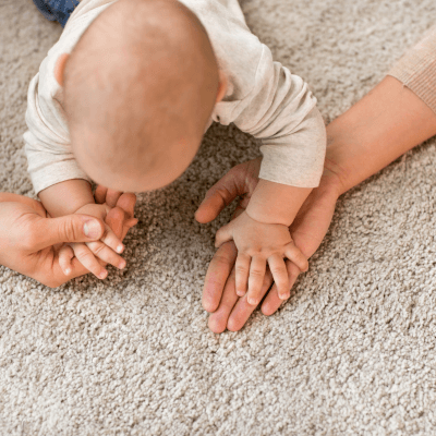 Baby crawling and holding mum and dad hand