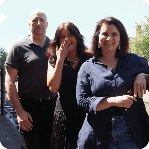 Man and 2 women standing for a photo with the woman in the middle laughing