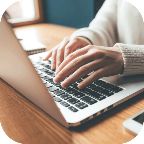 Hands working on a silve laptop.