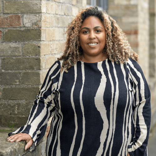 Chantal - a lady with brown and blond curled hair in a black and white striped dress