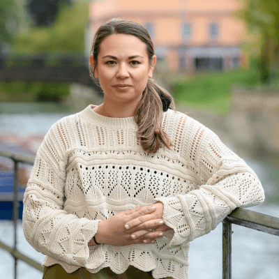 Jen Watton - a woman in a cream jumper stands against a railing