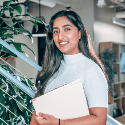Female with long dark hair holding a folder standing on some stairs