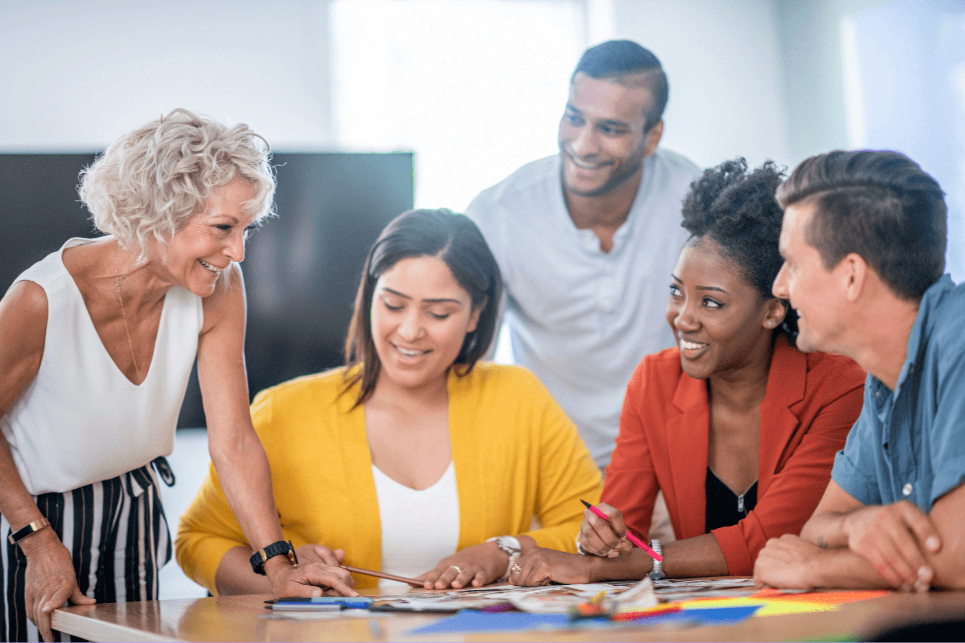 3 female employees and 2 male employees gather around notes to discuss work