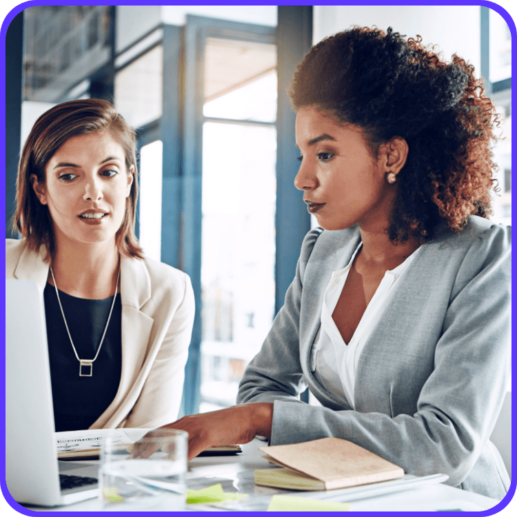 Two woman in an office, discussing work on a laptop