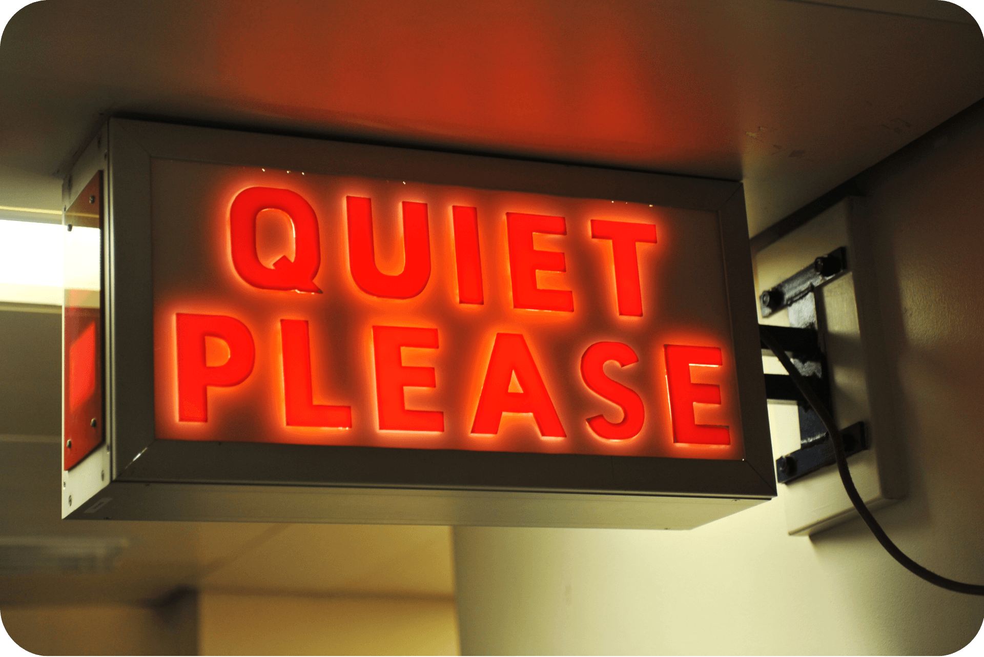 A red neon sign with the words quiet please