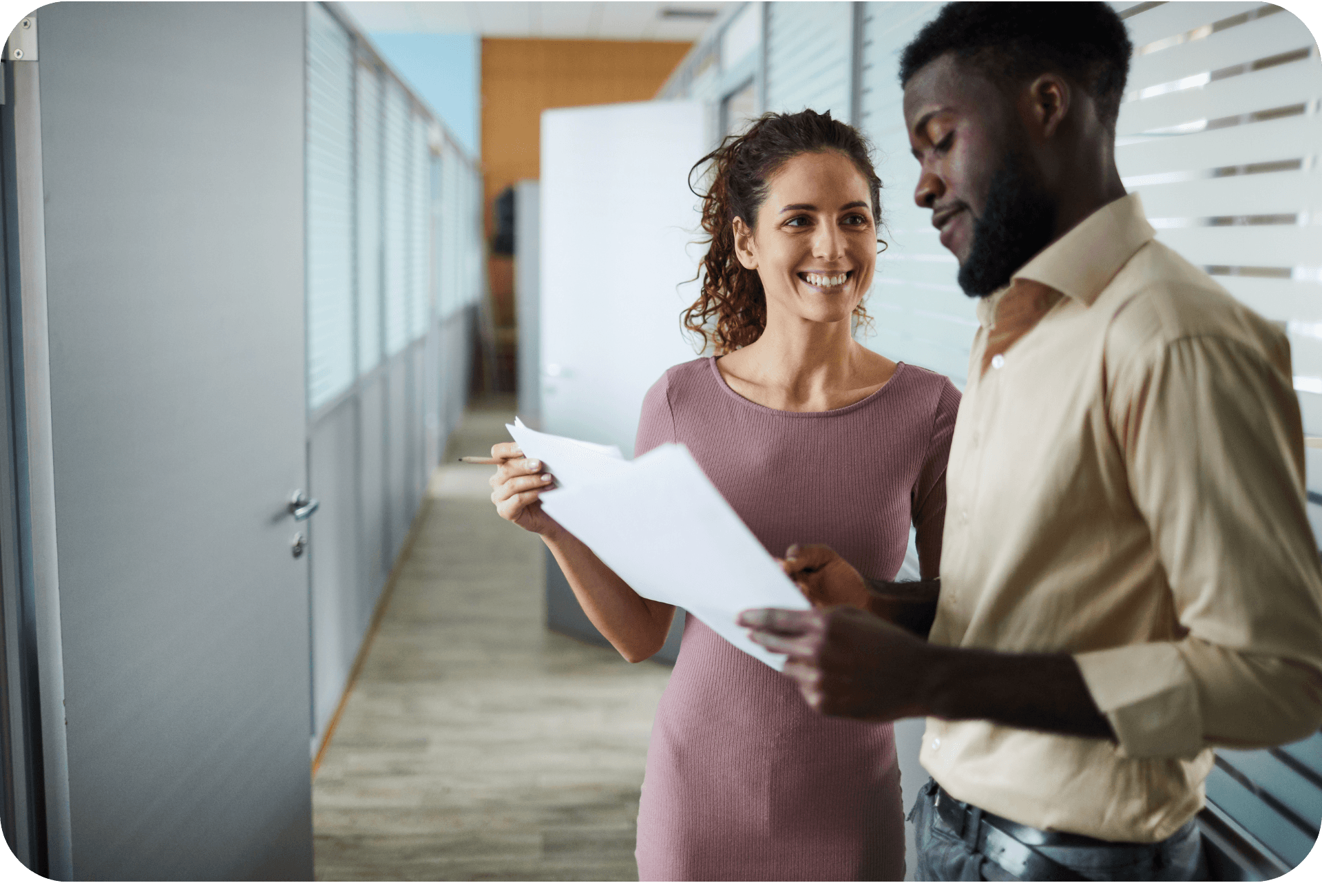 A female office worker and male office worker discussing work in the corridor