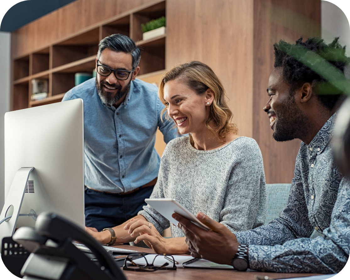 Three people sitting around a computer screen smiling