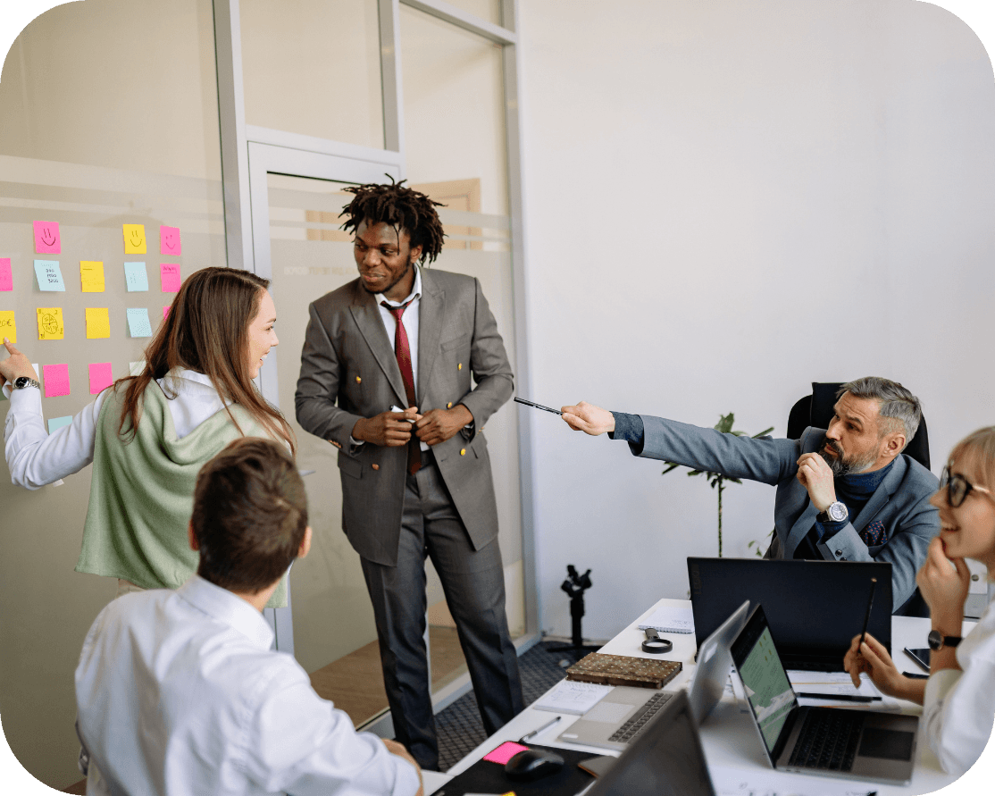 five office workers in a meeting room, discussing the contents of their meeting notes