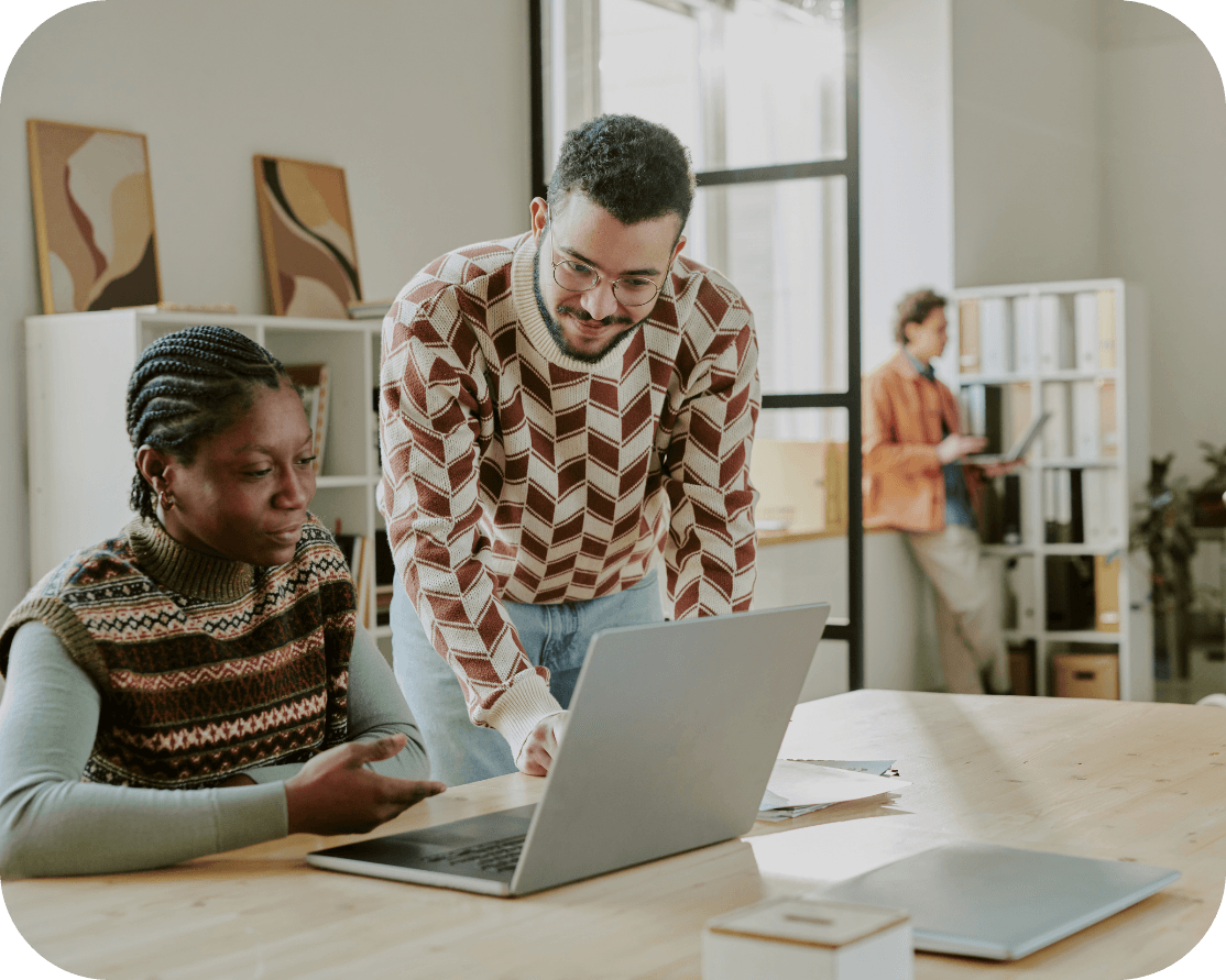 Two office workers, working together on a single laptop