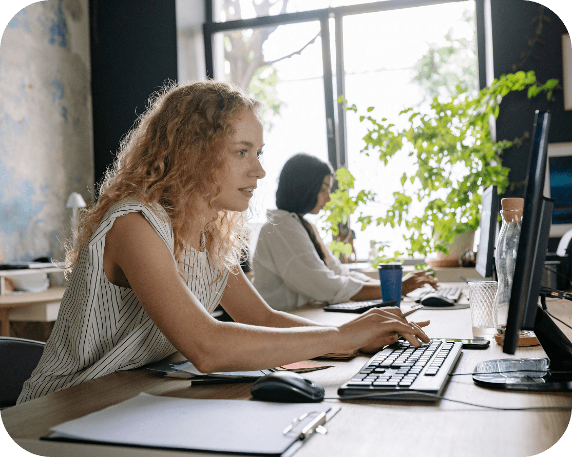 Red haired female, working on an office computer