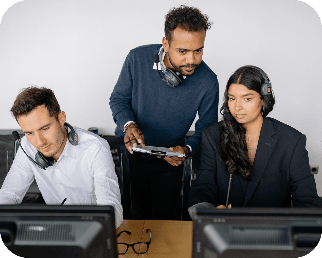 three office workers, one female and two males are discussing work displayed on their laptop screens
