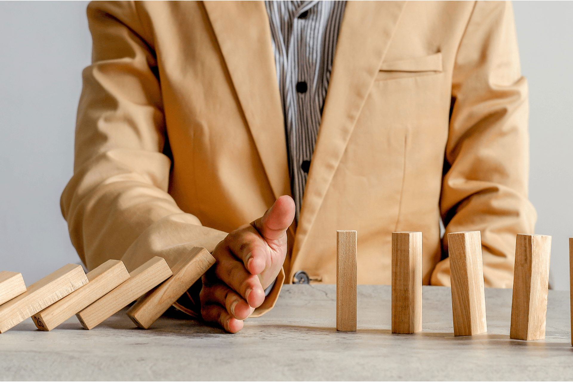 A male using their hand to stop the wooden dominoes from continuing to fall