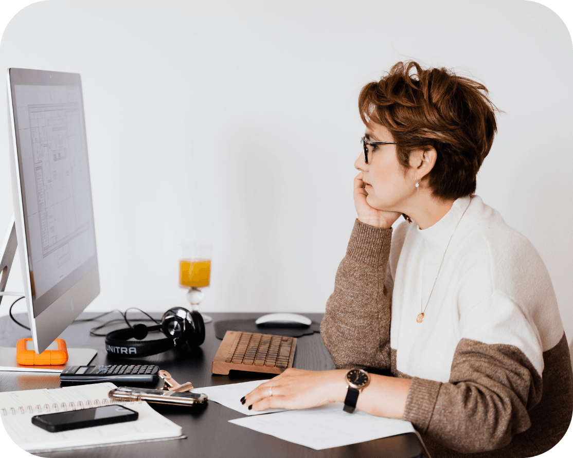 A female with short, brunette hair looking at their computer screen. They look deep in thought.